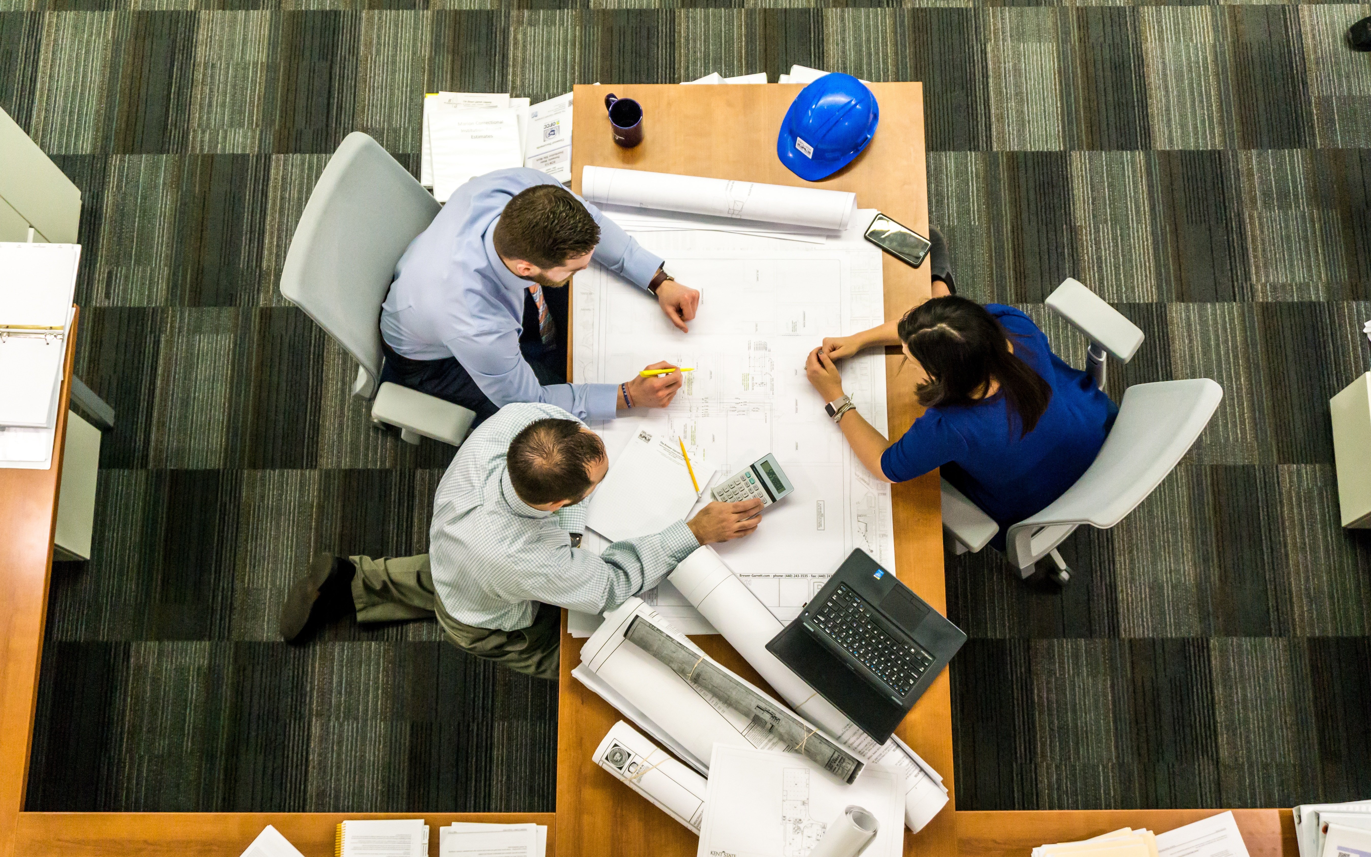 Overhead view of three people reviewing plans together at a table